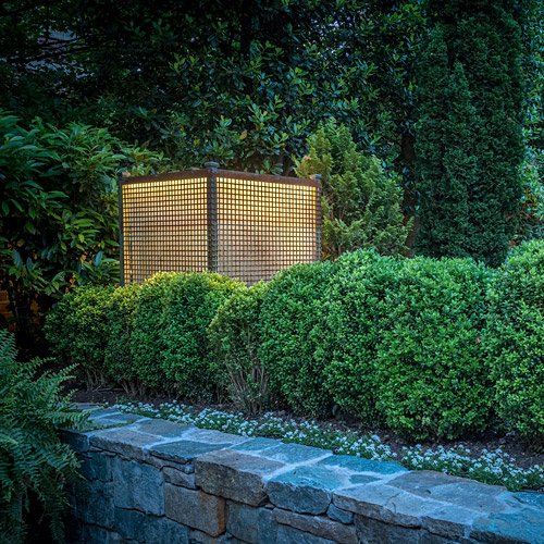 A garden lantern lighting a planted border after dusk