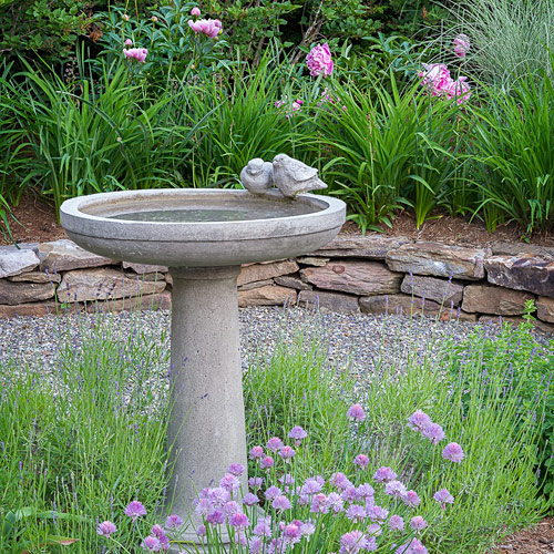 A stone bird bath set among low planting