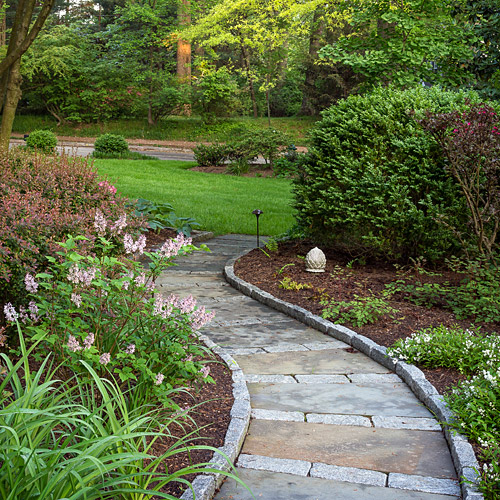 A curved stone path running between deep perennial borders